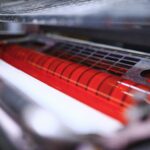 red ink on rollers of industrial offset printer during work in typography workshop.