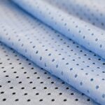 Blue mesh sport wear fabric textile pattern background. Blue color football jersey clothing fabric texture sports wear. Breathable porous poriferous material air ventilation with small holes