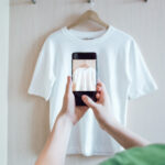 Woman is taking photo on smartphone of used clothing for resale or charity